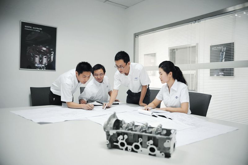 The picture shows MAPAL employees in Asia drawing up a turnkey project plan.